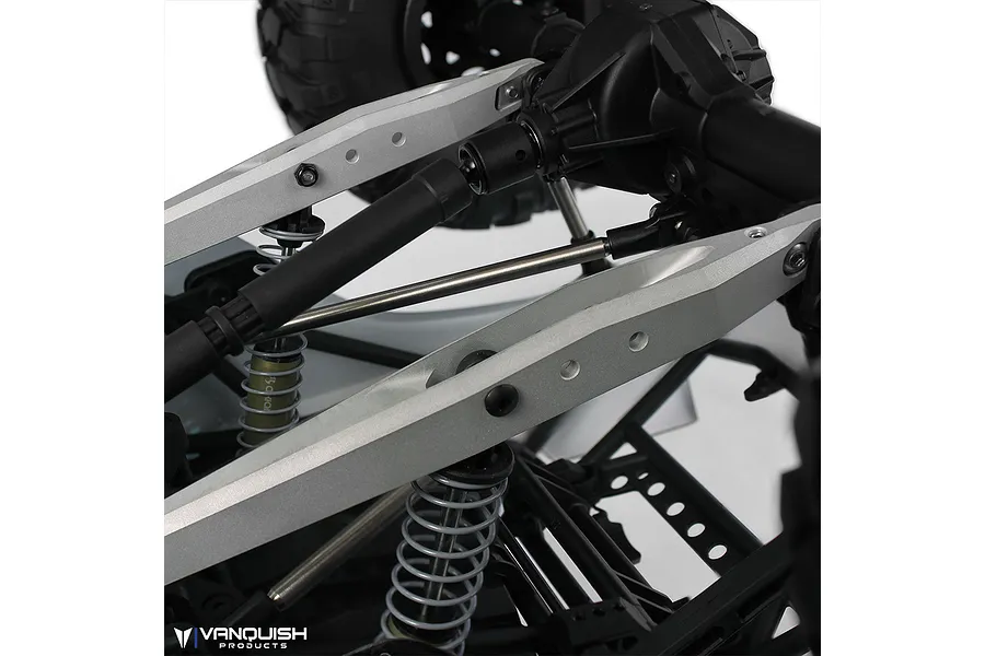Close-up of silver aluminium rear trailing arms installed on an RC vehicle chassis, showing suspension components and drive shaft.