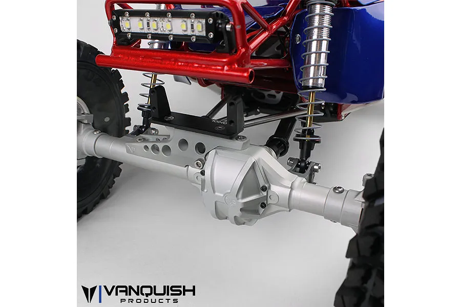 Close-up of a silver Vanquish aluminium axle housing installed on an RC rock crawler chassis with red frame and blue body panels.