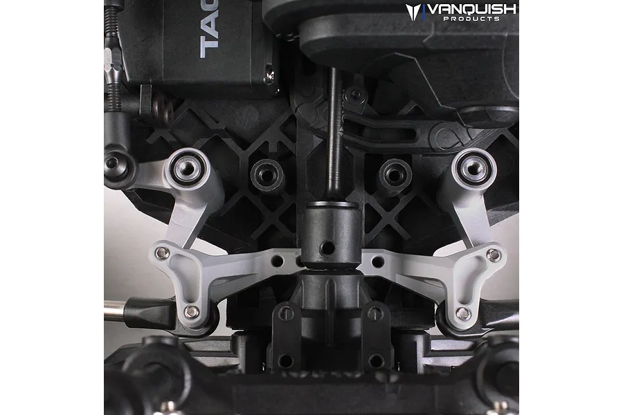 Close-up of silver aluminium steering bell crank set installed on a black RC vehicle chassis, showing the linkage and mounting points.