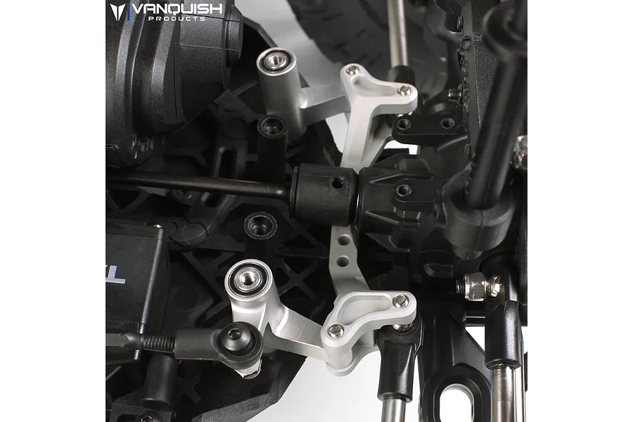 Close-up of a silver aluminium steering bell crank set installed on an RC vehicle chassis.