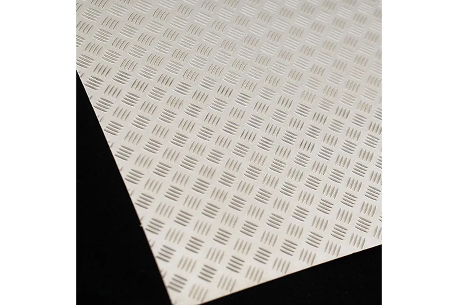 A close-up view of a silver-coloured metal sheet with a repeating diamond plate tread pattern.