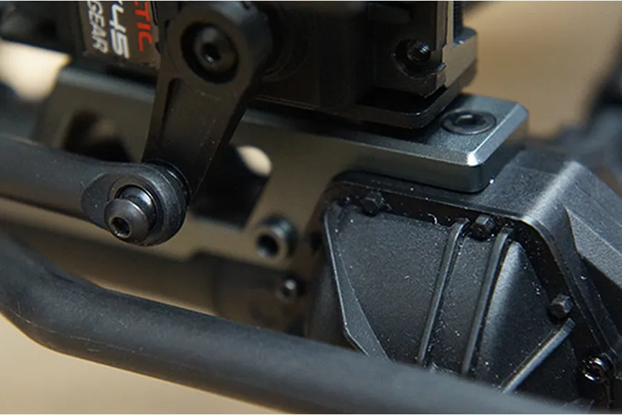 Close-up of a grey aluminium axle housing and steering servo mount installed on an RC crawler chassis.