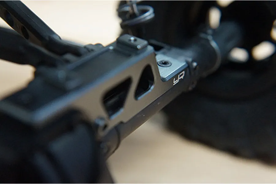 Close-up of a grey aluminium Yeah Racing suspension component installed on an RC vehicle chassis.