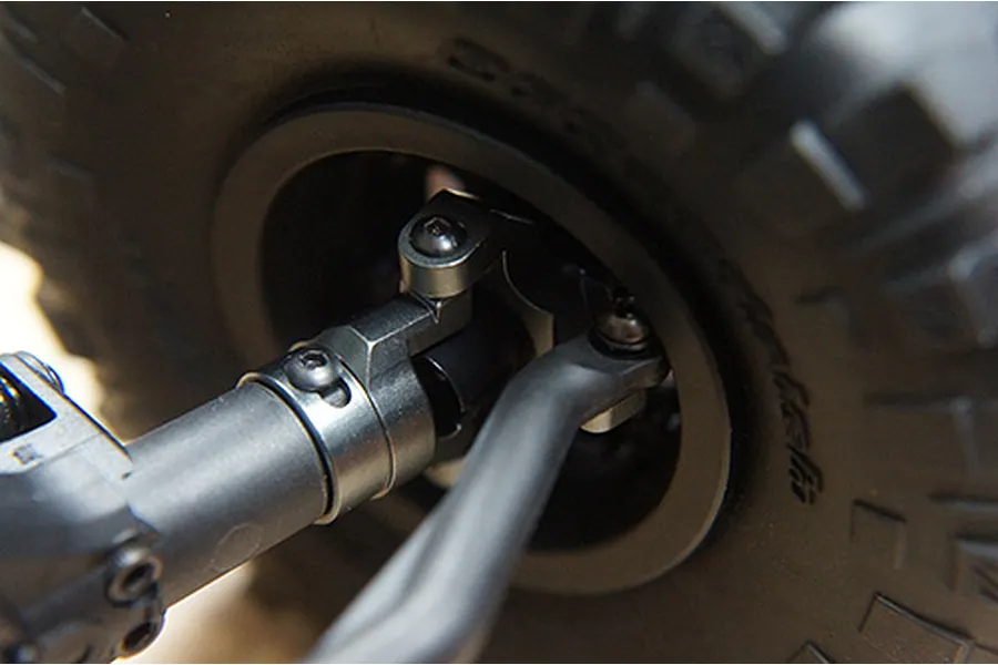Close-up of a grey aluminium steering knuckle and C-hub assembly installed on an RC crawler axle.