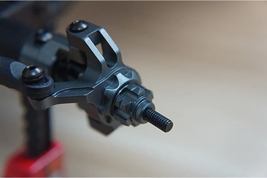 Close-up of a grey aluminium RC steering knuckle and wheel hex adapter installed on an axle.