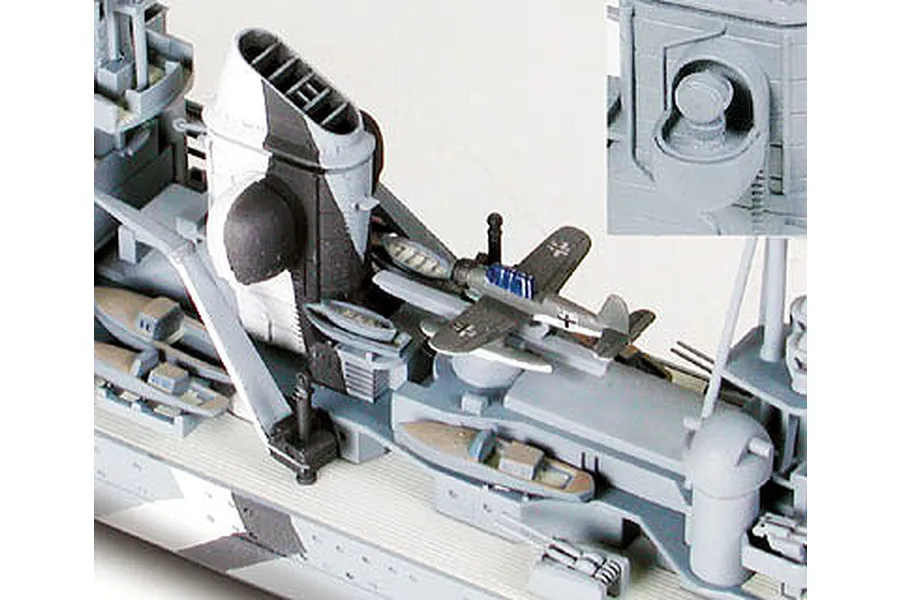 Close-up of a 1/700 scale Tamiya Prinz Eugen model ship deck, showing a small aircraft, funnel, and detailed deck structures.