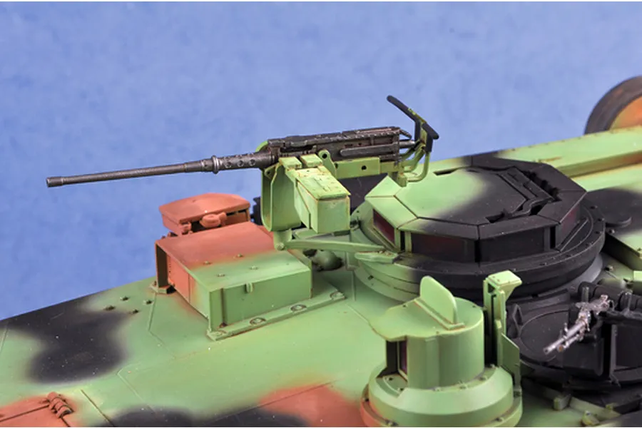 Close-up of the turret area of a 1/16 scale M1A1 Abrams model tank, showing the mounted machine gun and camouflage paint scheme.