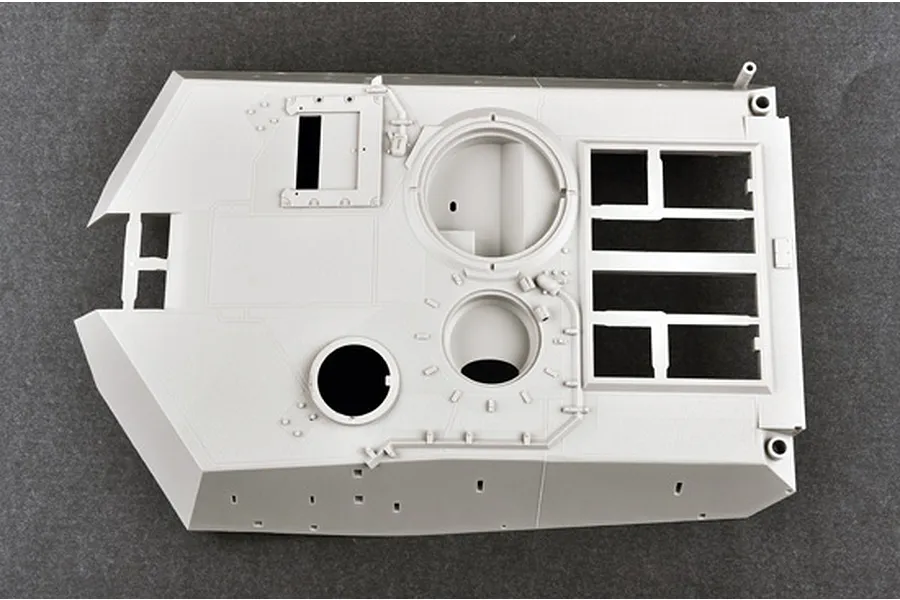 A top-down view of an unpainted light grey plastic model tank turret part from a Trumpeter 1/16 scale M1A1 Abrams kit.