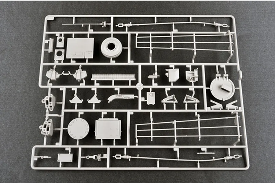 A grey plastic sprue containing various model tank parts, including frame sections, wheels, and small mechanical components for a 1/16 scale model kit.