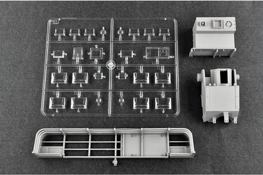 Plastic model kit parts for a 1/16 scale tank, including a clear sprue of windows and grey plastic components on a dark grey background.
