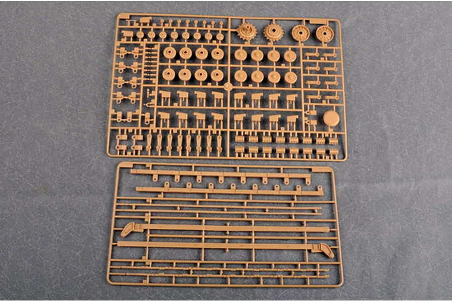 Two tan plastic model kit sprues containing various wheels, suspension parts, and structural beams on a grey background.