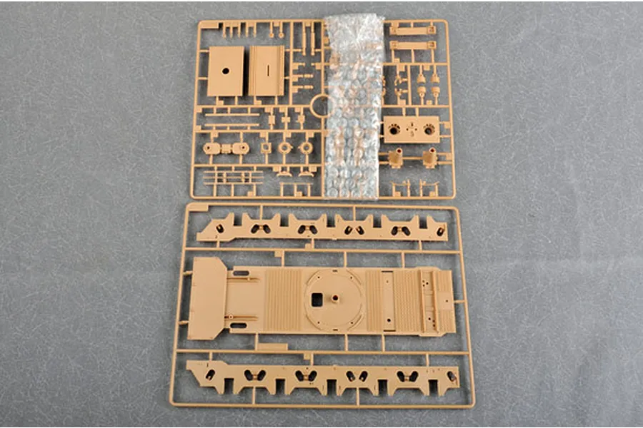 Two plastic model kit sprues for a 1/35 scale military vehicle, featuring tan plastic parts on a grey textured background.