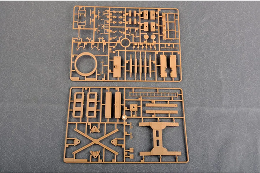 Two tan plastic model kit sprues containing various structural parts for a 1/35 scale military vehicle model, laid out on a grey surface.