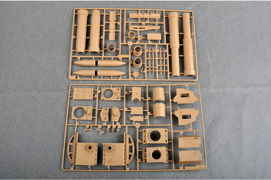 Two tan plastic model kit sprues containing various parts for a German Morser Karl self-propelled gun model, laid out on a grey surface.