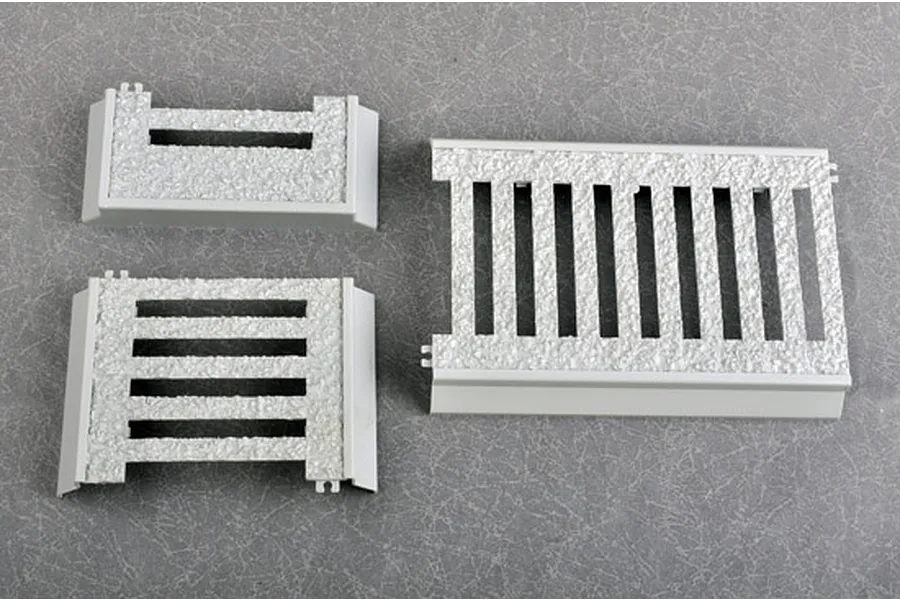 Three grey plastic model kit parts with textured surfaces, likely representing metal grating or flooring for a 1/35 scale military model.