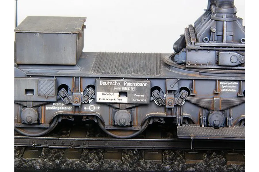 Close-up of a 1/35 scale model of a German Morser Karl railway transport carrier, showing detailed bogies, wheels, and Deutsche Reichsbahn markings.