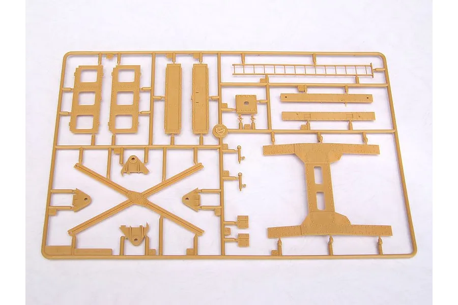 A tan plastic model kit sprue containing various structural parts for a military vehicle model.