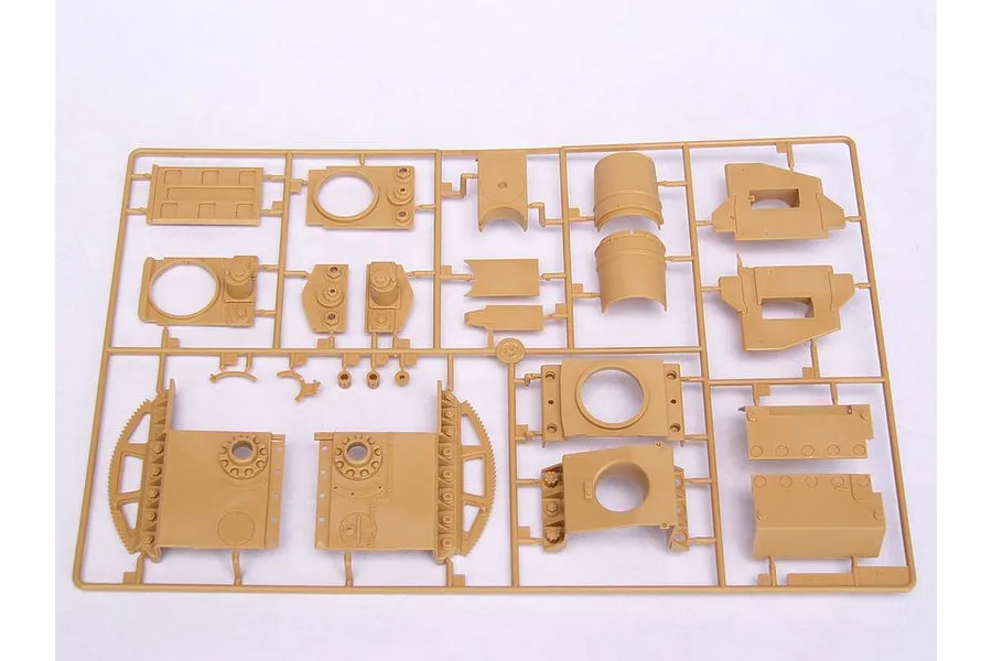 A tan plastic sprue containing various unpainted model kit parts for a military vehicle, laid out on a white surface.