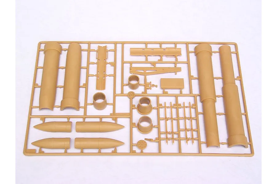 A tan plastic model kit sprue containing various cylindrical and structural parts for a military vehicle model.