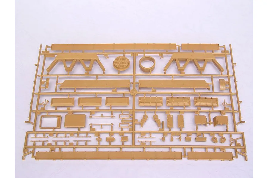A tan plastic sprue containing various model kit parts for a military vehicle, laid out on a white background.