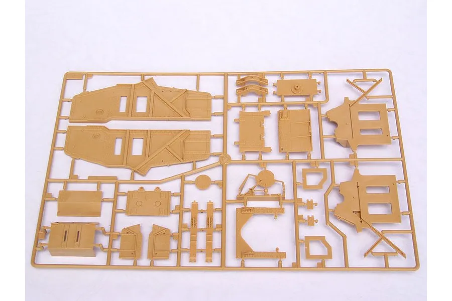 A tan plastic sprue containing various model kit parts for a military vehicle, including hull side panels and structural components.
