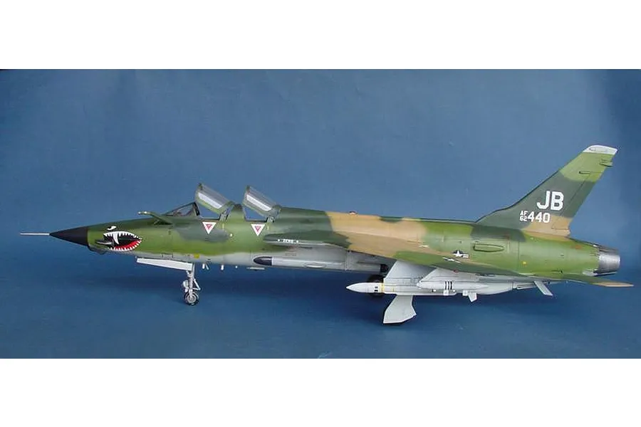 A side profile view of a finished 1/32 scale plastic model of a Republic F-105G Wild Weasel jet with camouflage paint and shark mouth nose art.
