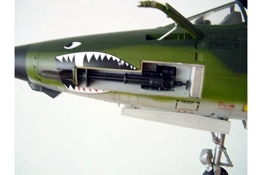Close-up of a 1/32 scale plastic model F-105G Wild Weasel jet showing the nose section with shark mouth decal and exposed M61 Vulcan cannon.