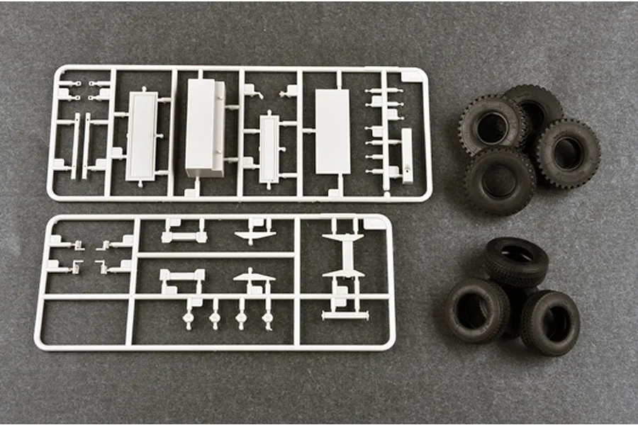 Two plastic model kit sprues and several black rubber tires for a 1/35 scale military vehicle model kit.