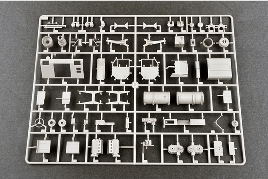 A grey plastic model kit sprue containing various vehicle parts for a 1/35 scale military model, laid out on a dark grey surface.