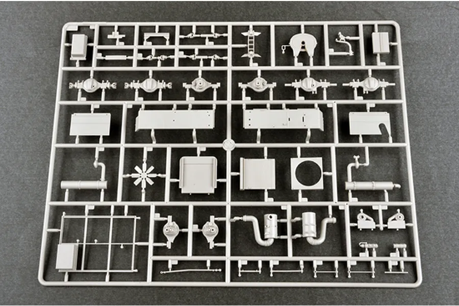 A grey plastic model kit sprue containing various vehicle parts, including axles, chassis components, and mechanical assemblies, on a dark grey background.