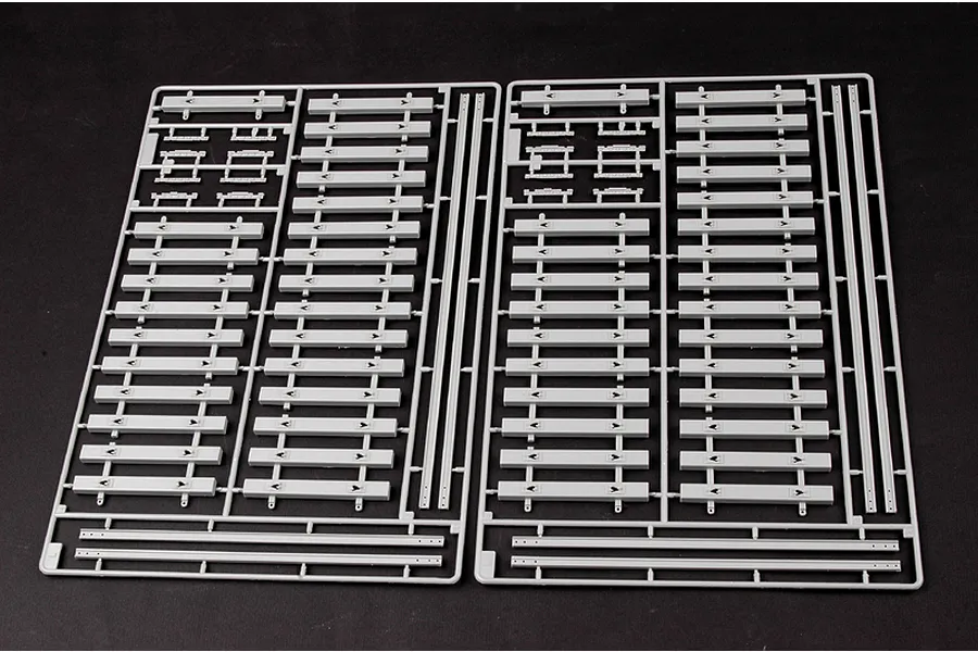 Two grey plastic model kit sprues containing multiple railway track sleeper components on a black background.