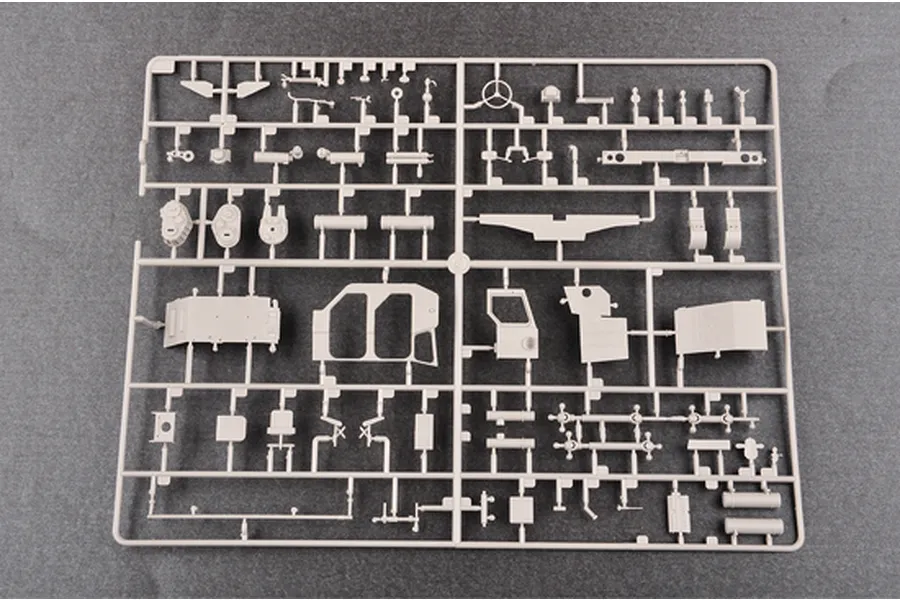 A light grey plastic model kit sprue containing various vehicle parts, including cabin panels, steering wheel, and interior components.