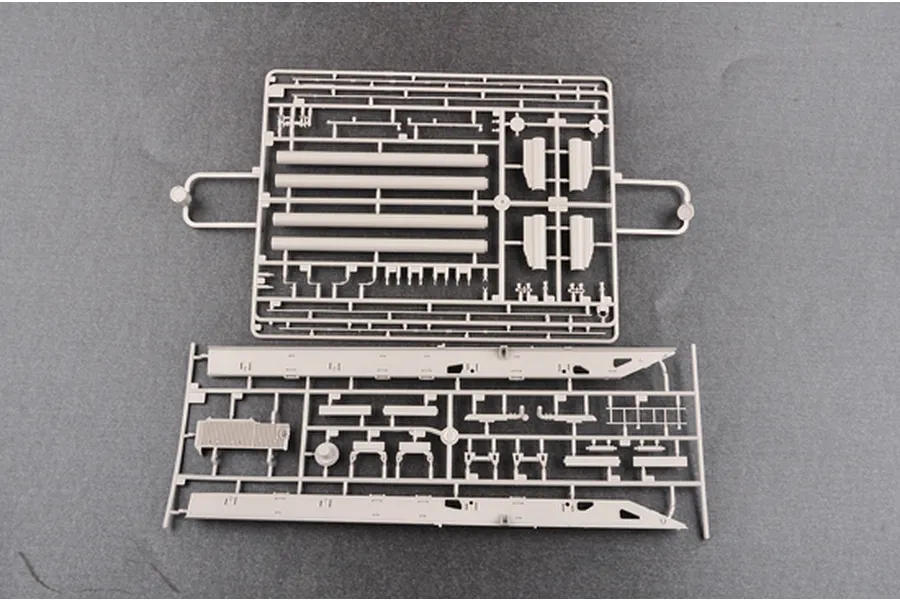 Two grey plastic model kit sprues containing various vehicle parts laid out on a dark grey surface.
