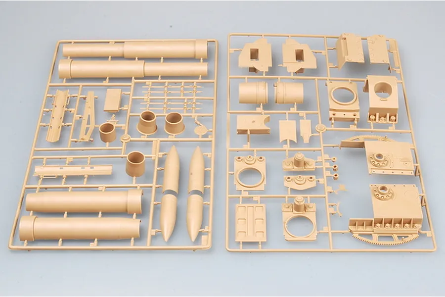 Two tan plastic model kit sprues containing parts for a large artillery piece, including barrel sections and structural components.