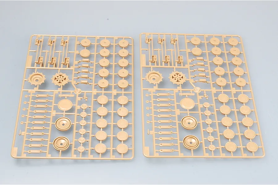 Two identical tan plastic model kit sprues featuring road wheels, sprockets, and suspension parts for a 1/35 scale military vehicle.