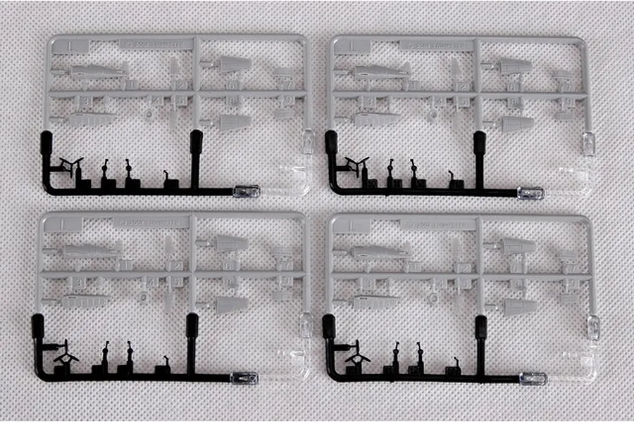 Four identical plastic model kit sprues containing small aircraft parts on a white textured background.