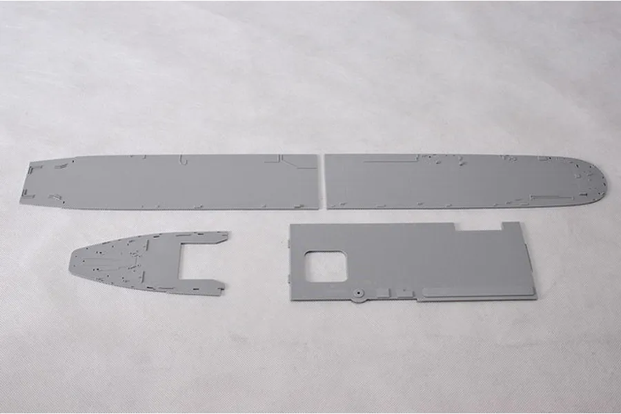 Four grey plastic model kit parts for an aircraft carrier flight deck laid out on a white background.