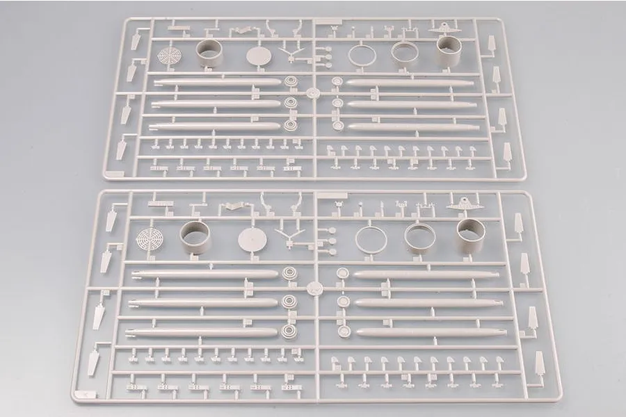 Two identical grey plastic model kit sprues containing various aircraft parts, including cylindrical components and small structural pieces.