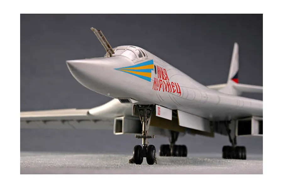 A front-angle view of a completed 1/72 scale Trumpeter TU-160 Blackjack bomber model kit, featuring white fuselage, Cyrillic markings, and landing gear.