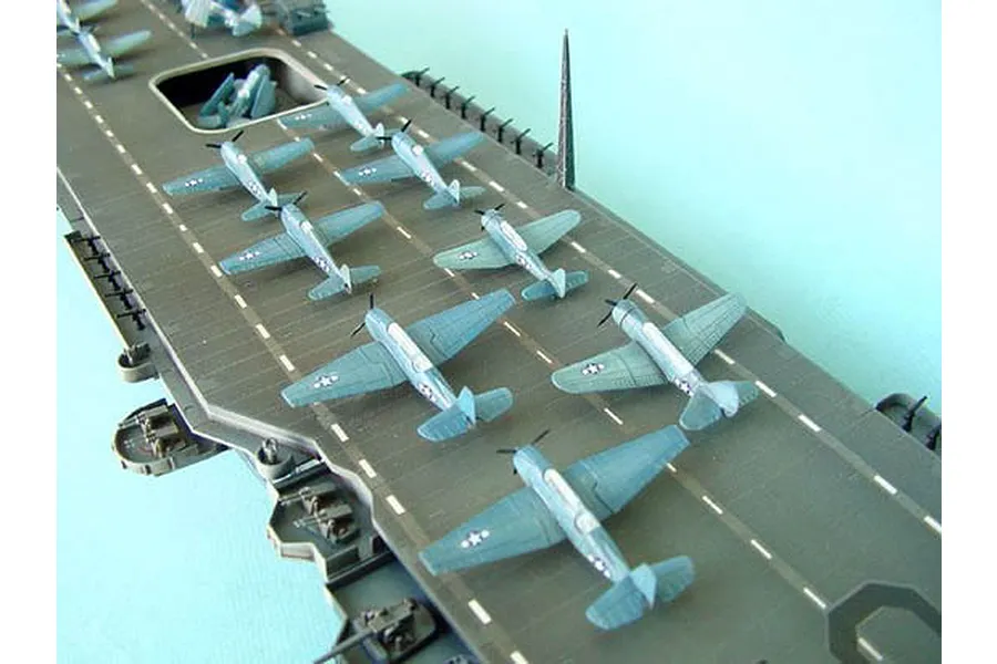 A high-angle close-up of a 1/350 scale model aircraft carrier deck with several small grey US Navy fighter planes parked on the flight deck.