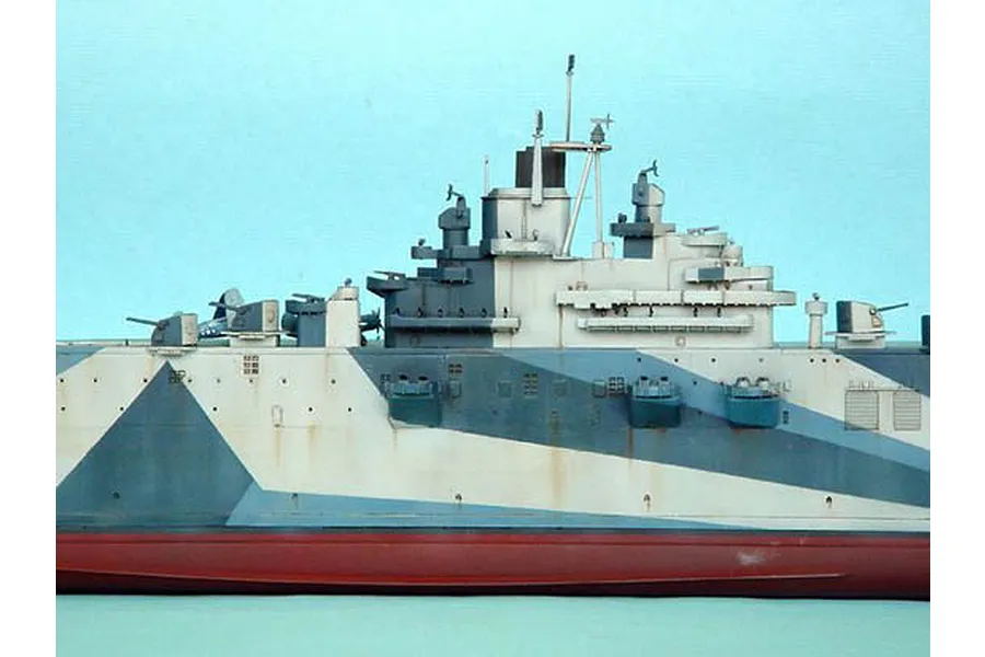 Side view of a 1/350 scale plastic model of the USS Yorktown aircraft carrier featuring a blue and white dazzle camouflage paint scheme.