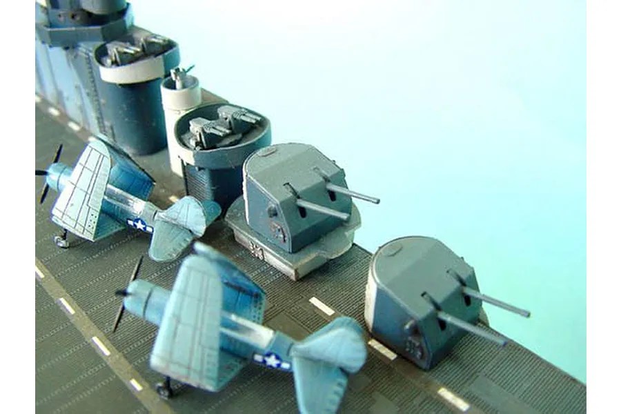 Close-up of a 1/350 scale model aircraft carrier deck featuring miniature fighter planes and anti-aircraft gun turrets.