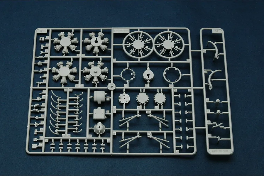 A grey plastic sprue containing various aircraft engine and structural parts for a 1/32 scale model kit, set against a dark blue background.