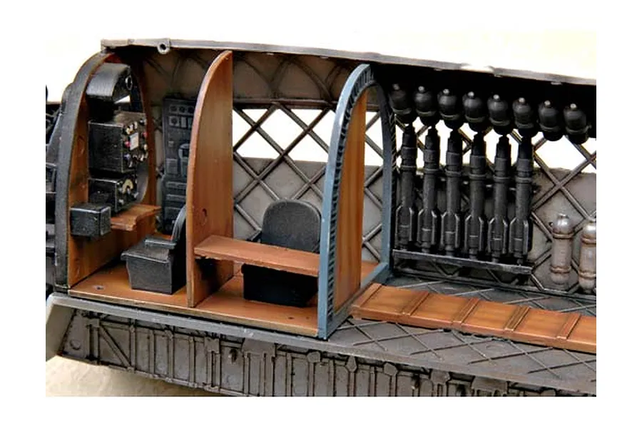 Interior view of a scale model Wellington bomber fuselage showing cockpit seats, bulkheads, and a bomb rack with hanging ordnance.