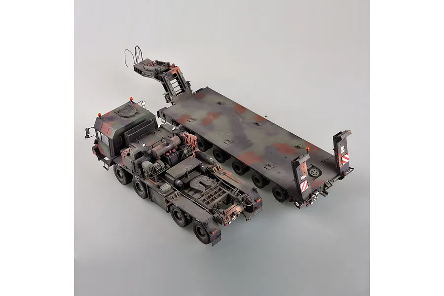 A high-angle studio shot of a 1/35 scale German Faun SLT-56 tank transporter model kit, featuring a camouflaged truck and detached flatbed trailer.
