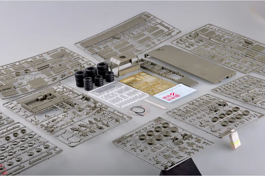 A collection of plastic model kit parts for a 1/35 scale German Faun SLT-56 tank transporter, including sprues, rubber tires, photo-etched parts, and decals.