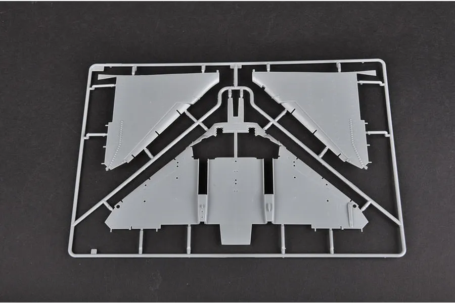A grey plastic sprue containing aircraft wing components for a model kit, viewed from above against a dark background.
