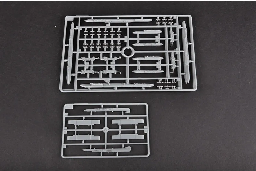 Two grey plastic model kit sprues containing various aircraft parts and weapon pylons on a dark background.