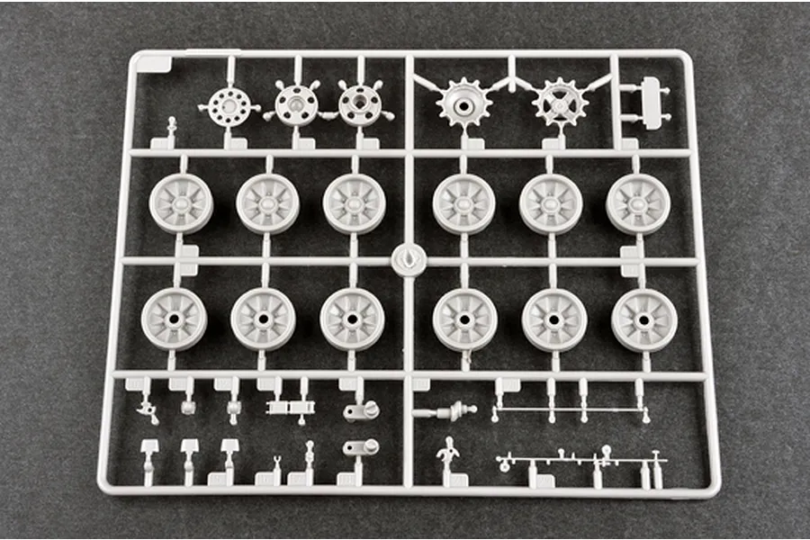 A grey plastic model kit sprue containing various tank wheels, sprockets, and small mechanical parts for a 1/35 scale military vehicle model.
