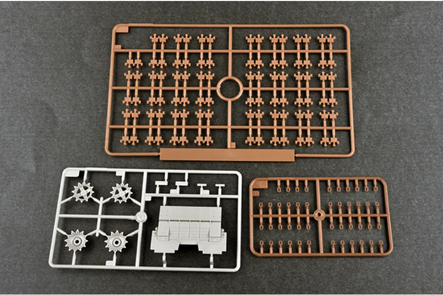Three plastic model kit sprues from a Trumpeter 1/35 scale tank kit, including track links and drive sprockets on a dark grey surface.